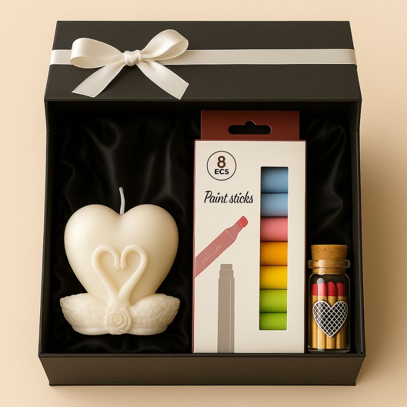 Coffret Bougie à Décorer Cœur Lunaire, la bougie blanche en forme de cœur et de cygne, les feutres cires et les allumettes, le tout dans un coffret cadeaux. Fond beige clair.