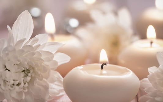 Bougies blanches allumées entourées de fleurs claires, créant une ambiance douce, apaisante et élégante pour une décoration intérieure lumineuse et raffinée.