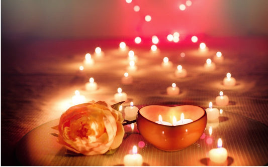 Bougie parfumée allumée entourée de petites flammes scintillantes, créant une ambiance chaleureuse et féerique aux tons dorés et rosés.