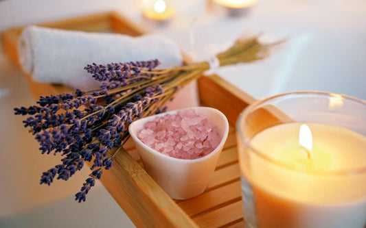 Bougie parfumée allumée avec bouquet de lavande et sel rose dans un petit bol en forme de cœur, posés sur un plateau en bois, ambiance bien-être et détente.