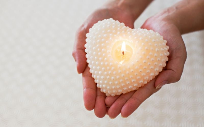 Bougie décorative en forme de cœur tenue dans les mains, symbole d’amour et idée cadeau romantique pour ambiance chaleureuse.