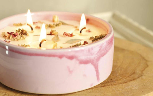 Bougie décorative allumée avec fleurs séchées dans un contenant rose pour une ambiance cosy à la maison.