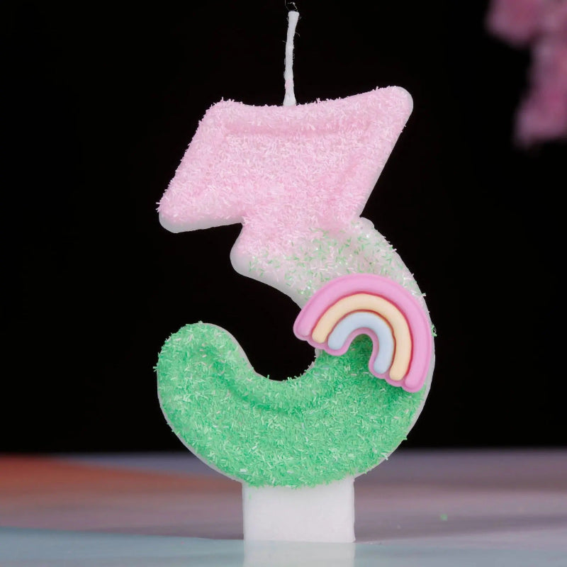 Bougie Anniversaire Arc en Ciel Enchanté, de couleur rose et vert, le chiffre de la bougie est le 3 et sur un fond noir.