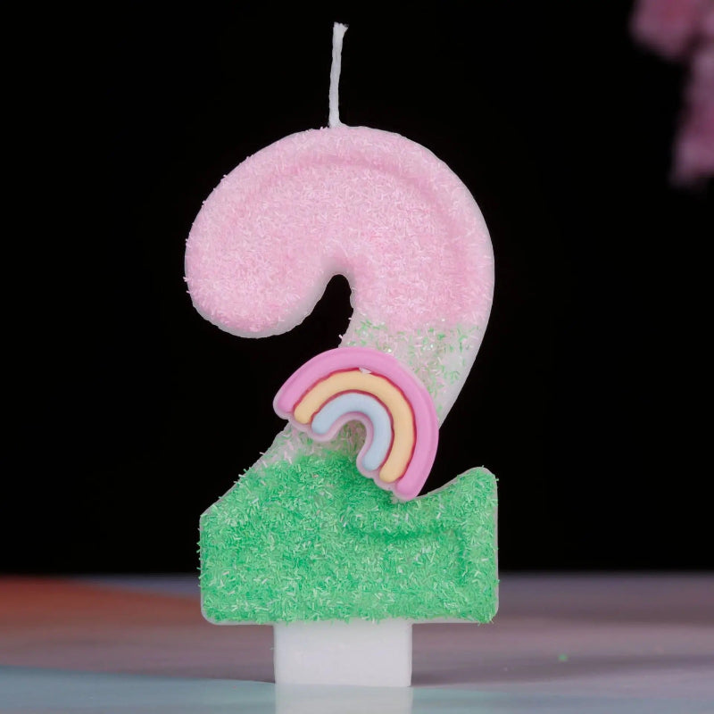 Bougie Anniversaire Arc en Ciel Enchanté, de couleur rose et vert, le chiffre de la bougie est le 2 et sur un fond noir.