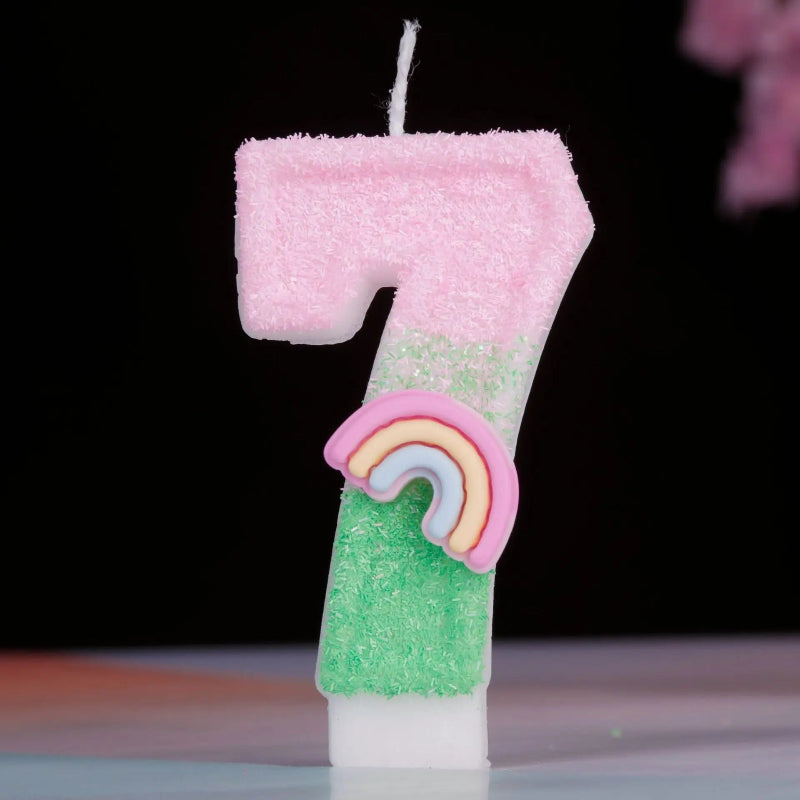 Bougie Anniversaire Arc en Ciel Enchanté, de couleur rose et vert, le chiffre de la bougie est le 7 et sur un fond noir.