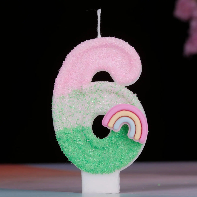Bougie Anniversaire Arc en Ciel Enchanté, de couleur rose et vert, le chiffre de la bougie est le 6 et sur un fond noir.