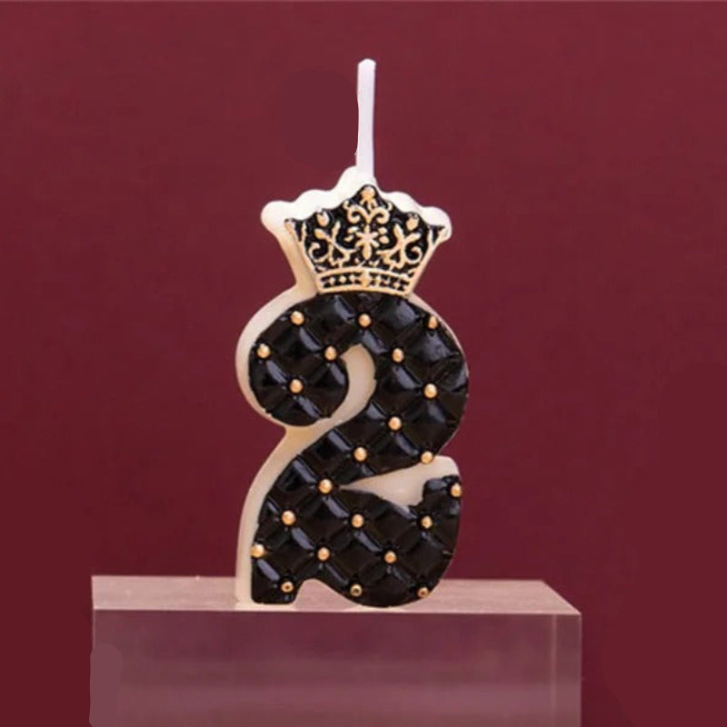 Bougie Anniversaire Chiffre Couronne Chic Noir et Or, sur un poduim en bois et sur fond rouge.