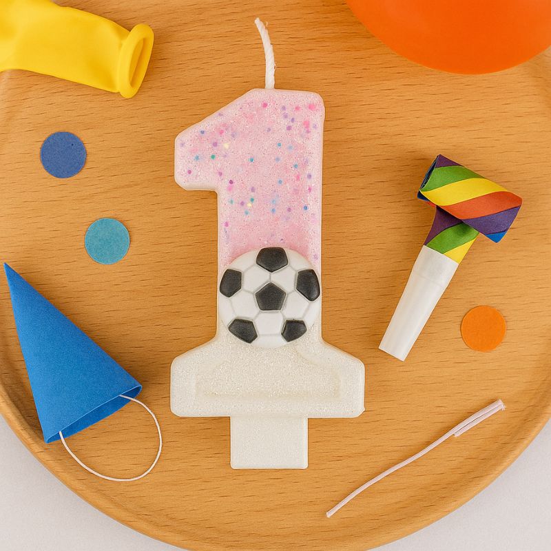 Bougie Anniversaire Coup d’Envoi Enchanté, le chiffre de la bougie est le 1, posé sur un plateau en bois avec des objets festifs.