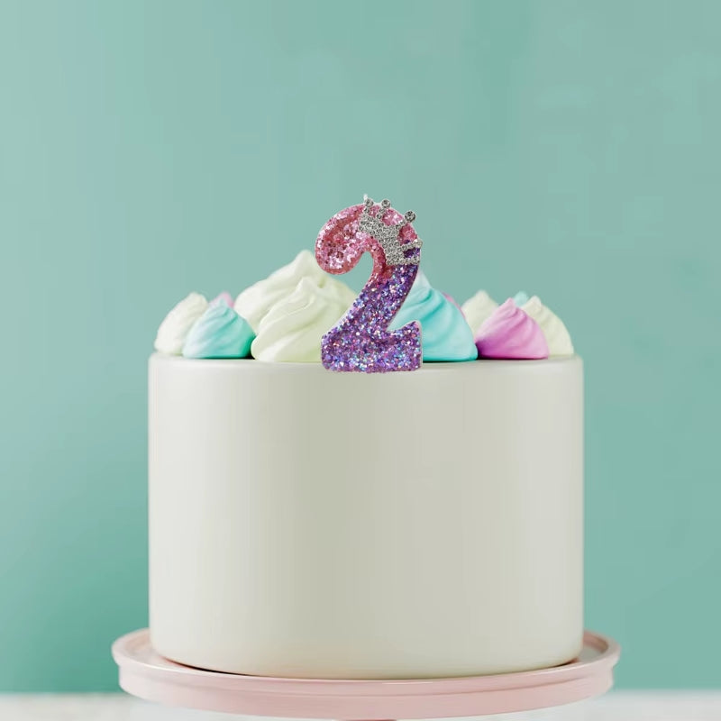Bougie Anniversaire Couronnée de Lumière, disposée sur un gâteau d’anniversaire et sur fond vert clair. Le chiffre de la bougie est le 2.