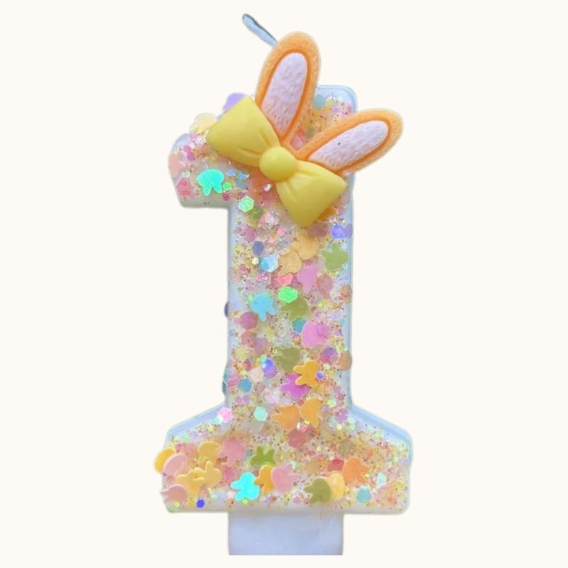 Bougie Anniversaire Douce Fantaisie, avec des paillettes multicolores, le chiffre de la bougie est le 1 et sur fond beige.