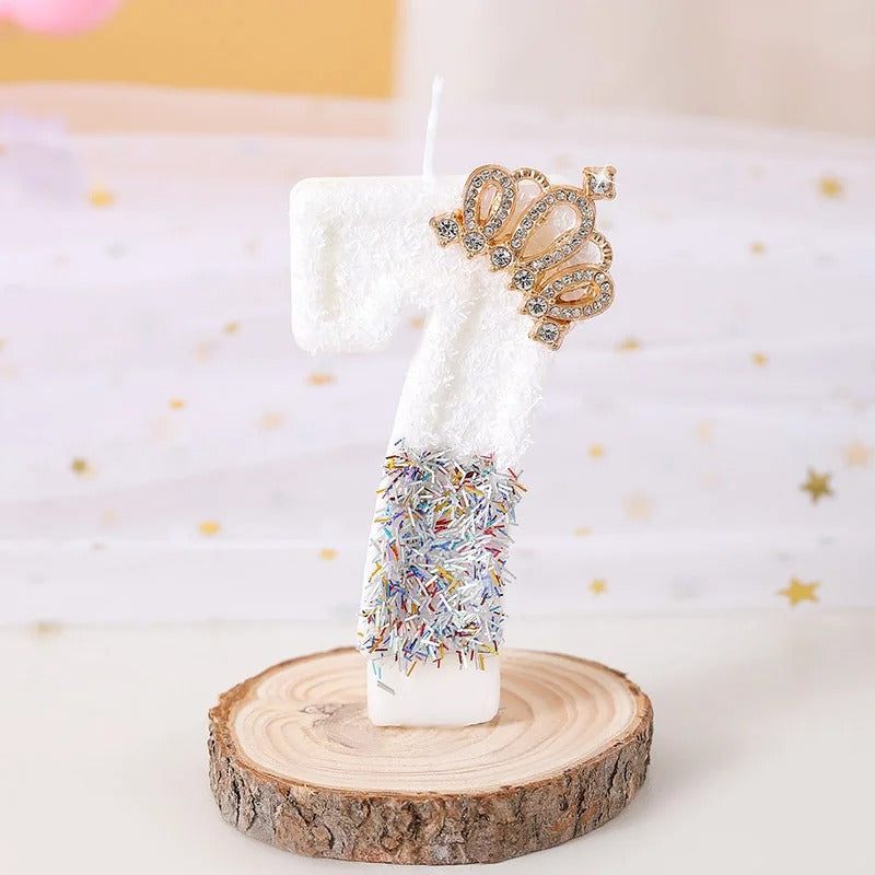 Bougie Anniversaire Édition Prestige, le chiffre de la bougie est le 7, de couleur blanche avec une couronne dorée et posée sur un rondin de bois.