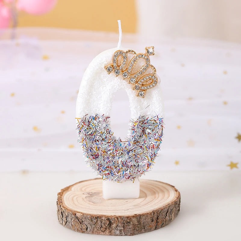 Bougie Anniversaire Édition Prestige, le chiffre de la bougie est le 0, de couleur blanche avec une couronne dorée et posée sur un rondin de bois.