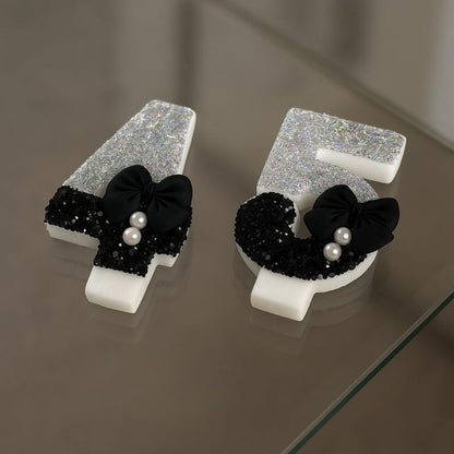 Bougie Anniversaire Nœud Chic, les chiffres sont le 4 et le 5 posées sur une table en verre.