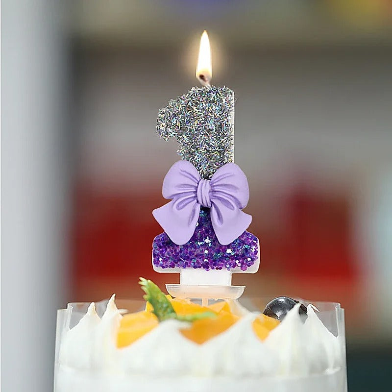 Bougie Anniversaire Noeud Romantique, allumée, disposée sur un gâteau d'anniversaire. Le chiffre représenté est le 1.