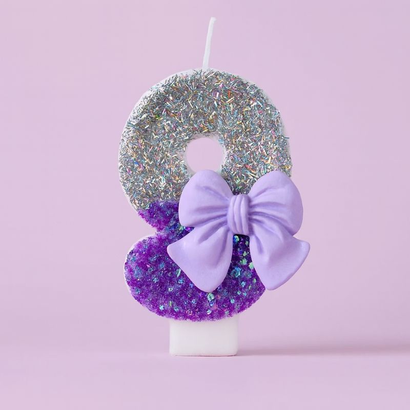 Bougie Anniversaire Noeud Romantique, de couleur violette et argentée, avec un noeud, le chiffre représenté est le 9. Sur fond violet pastel.