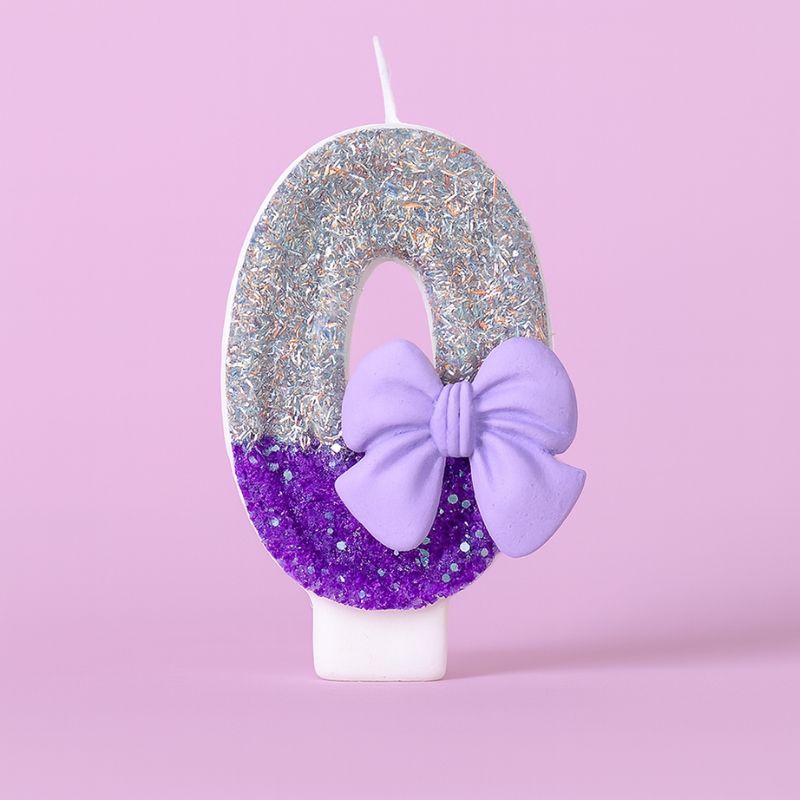 Bougie Anniversaire Noeud Romantique, de couleur violette et argentée, avec un noeud, le chiffre représenté est le 0. Sur fond violet pastel.