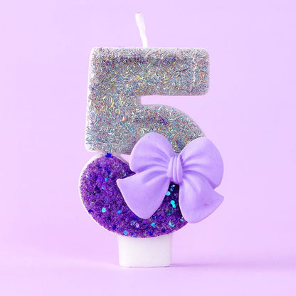 Bougie Anniversaire Noeud Romantique, de couleur violette et argentée, avec un noeud, le chiffre représenté est le 5. Sur fond violet pastel.