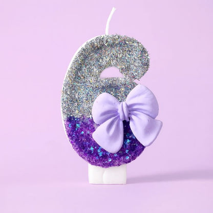 Bougie Anniversaire Noeud Romantique, de couleur violette et argentée, avec un noeud, le chiffre représenté est le 6. Sur fond violet pastel.