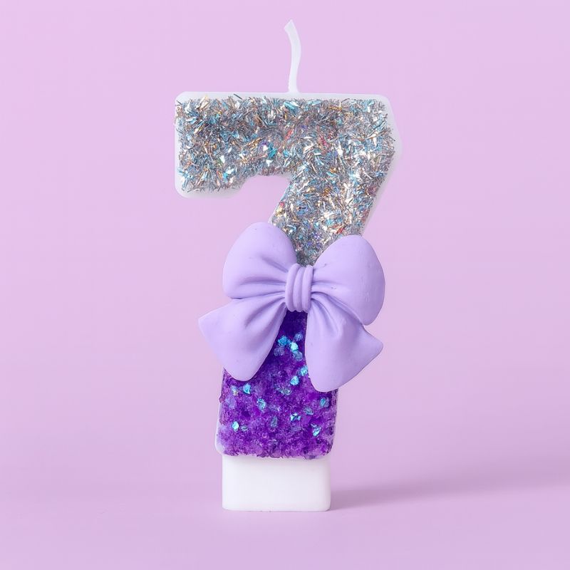Bougie Anniversaire Noeud Romantique, de couleur violette et argentée, avec un noeud, le chiffre représenté est le 7. Sur fond violet pastel.