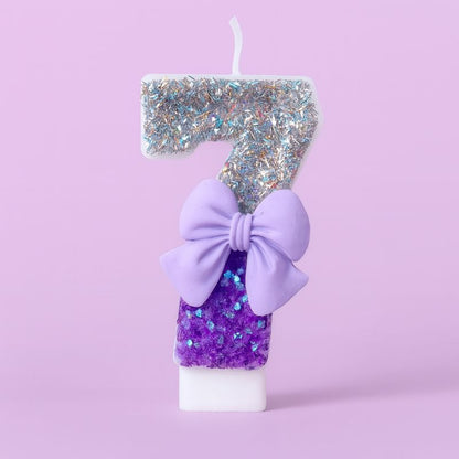 Bougie Anniversaire Noeud Romantique, de couleur violette et argentée, avec un noeud, le chiffre représenté est le 7. Sur fond violet pastel.