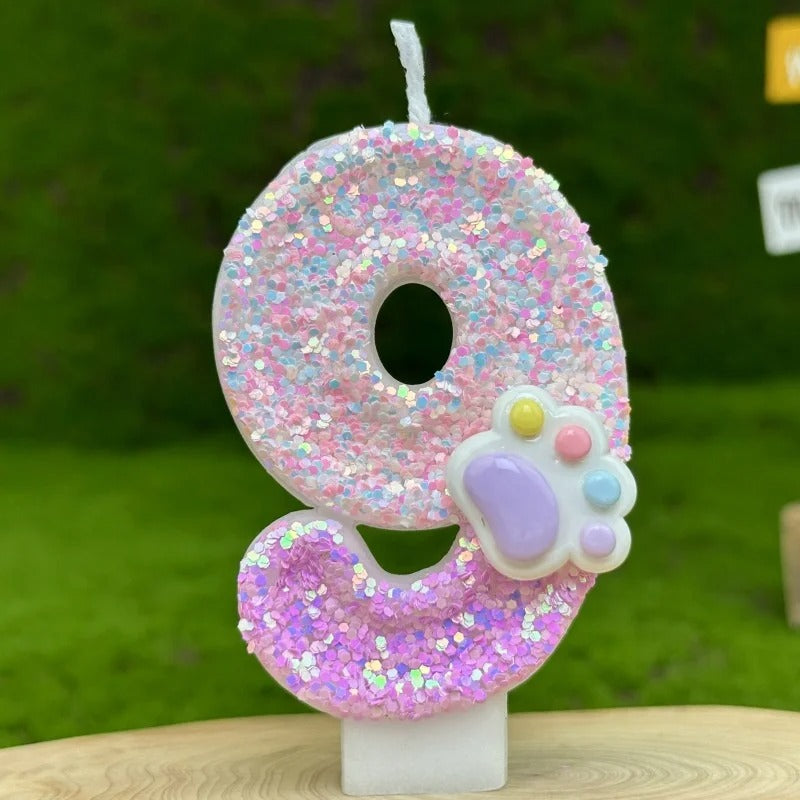 Bougie Anniversaire Patte Féline Scintillante, de couleur rose avec une patte d’animal dessus, le chiffre représenté est le 9 et sur fond vert.