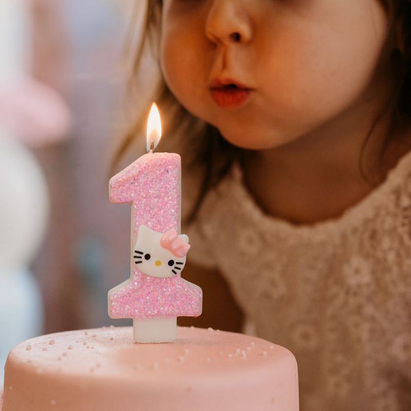 Bougie Anniversaire So Cute, le chiffre est le 1, la bougie est allumée sur le gâteau d’anniversaire et une petite fille souffle ses bougies.