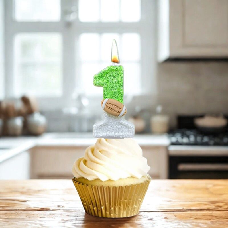 Bougie Anniversaire Thème Rugby, de couleur blanche et verte, le chiffre de la bougie est le 1 et disposée sur un cupcake posé sur une planche en bois dans une cuisine.