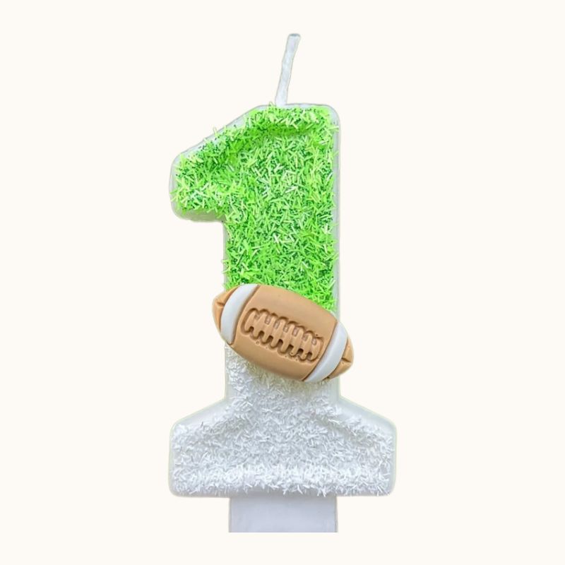 Bougie Anniversaire Thème Rugby, de couleur blanche et verte, le chiffre de la bougie est le 1 et sur fond beige.