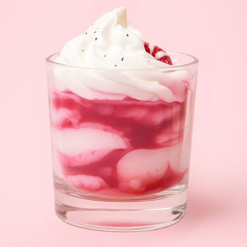 Bougie Bijou Cadeau Raffiné, de couleur rose et blanche avec des petits sucres d'orge et sur fond rose pâle.