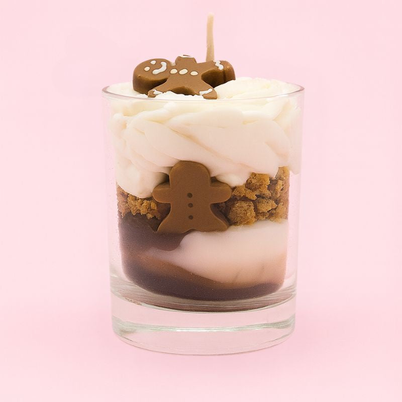 Bougie Bijou Magie Cachée, de couleur marron avec sa chantilly blanche, il y a aussi des adorables bonhommes pains d'épices et sur fond rose pâle.