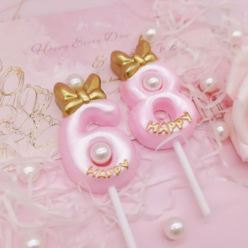 Bougie Chiffre Rose Girly et Chic, le chiffre 6 et 8 disposées sur une nappe rose avec des perles.