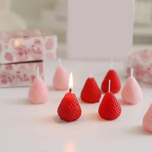 Bougie Décorative Fruit Fraise, posé sur une table, une bougie allumée et les autres éteintes.