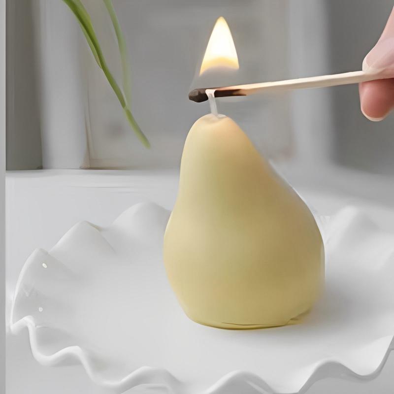 Bougie Décorative Fruit Poire, disposée dans une assiette et bougie allumée.