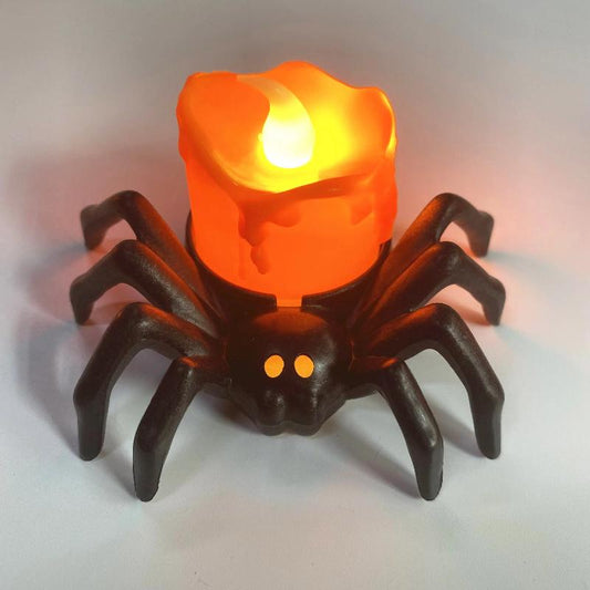 Bougie Halloween Led Araignée Noire, disposée sur une table et la bougie est allumée.