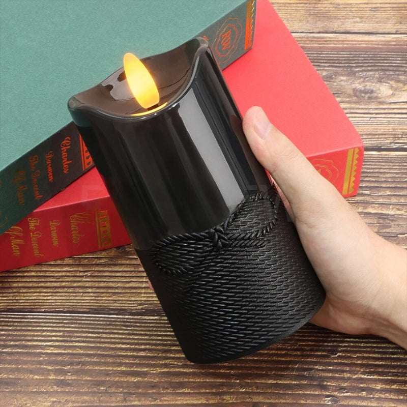 Bougie Halloween LED Pilier Noir Avec Petit Nœud, tenu par une main et sur un bureau en bois.