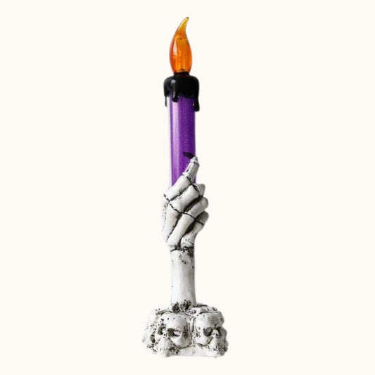 Bougie Halloween Lumière Hantée, de couleur blanche et violette et de forme tête de mort. Sur fond beige clair.