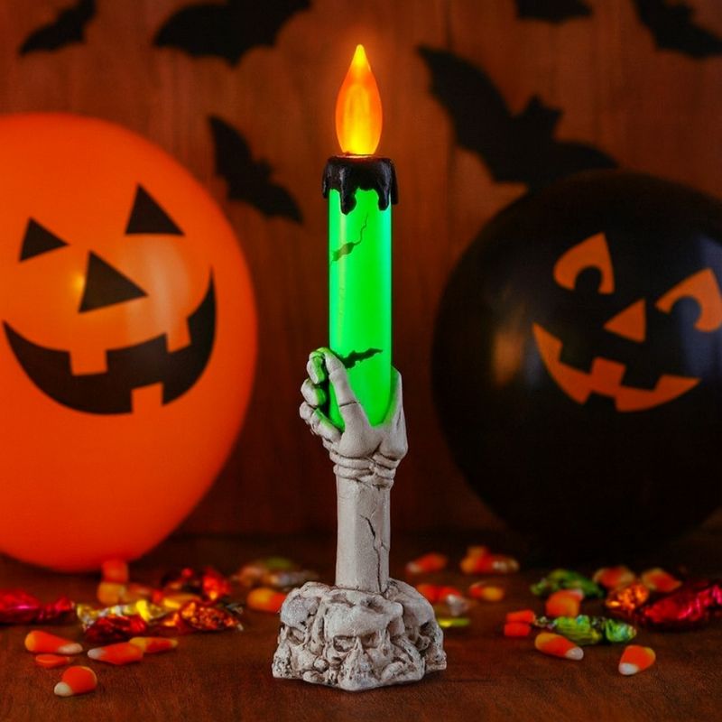 Bougie Halloween Lumière Hantée, de couleur blanche et verte, bougie à LED avec des têtes de mort. Décors festifs avec des ballons et des bonbons.
