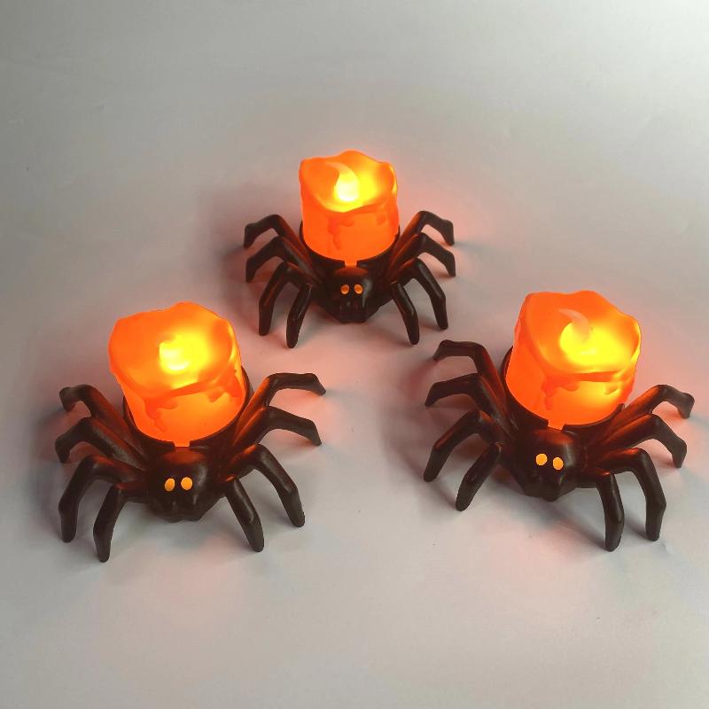 Bougie Halloween Terreur Lumineuse, 3 bougies en forme d'araignée et posée sur une table grise.