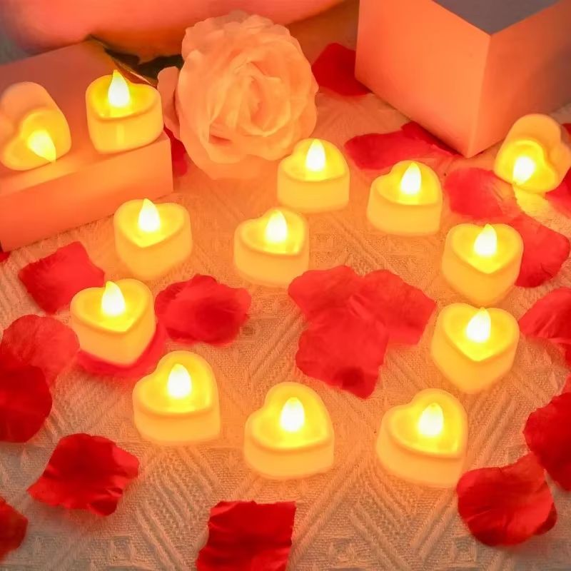 Bougie LED Chauffe Plat Cœur, disposées sur une table aumilieu de pétales de rose rouge.
