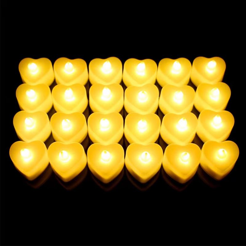 Bougie LED Chauffe Plat Cœur allumée et sur fond noir. Pack de 48 pièces.