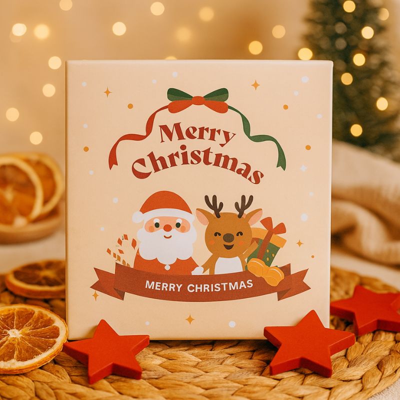 Bougie Noël Bonhomme Pain d’Épices, on voit l’arrière de la boîte cadeau qui dit Joyeux Noël. Ambiance festive.