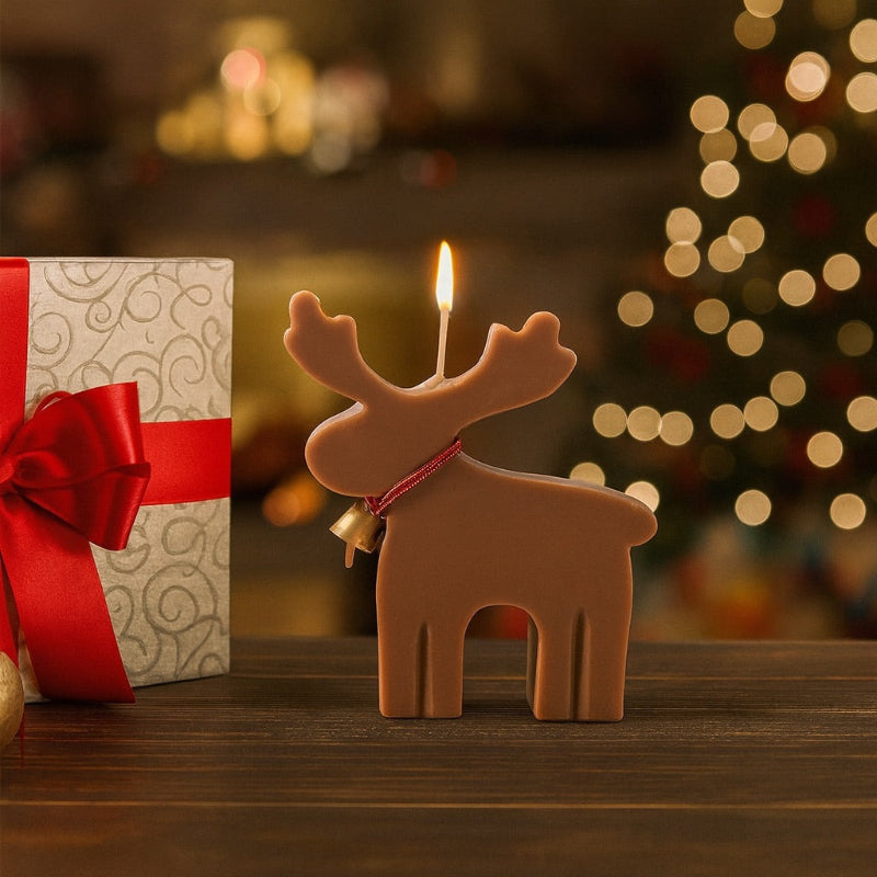 Bougie Noel Féérie du Renne Enchanté, de couleur beige clair et allumé, posée sur une table en bois. Ambiance festive.