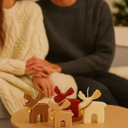 Bougie Noel Féérie du Renne Enchanté, il y a plusieurs couleurs représentées, rouge, beige, blanc et marron. On peut voir 2 adultes assis sur un canapé en arrière-plan.