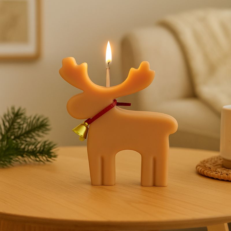 Bougie Noel Féérie du Renne Enchanté, de couleur beige clair et la bougie est allumée. Elle est posée sur une table en bois. Ambiance scandinave.