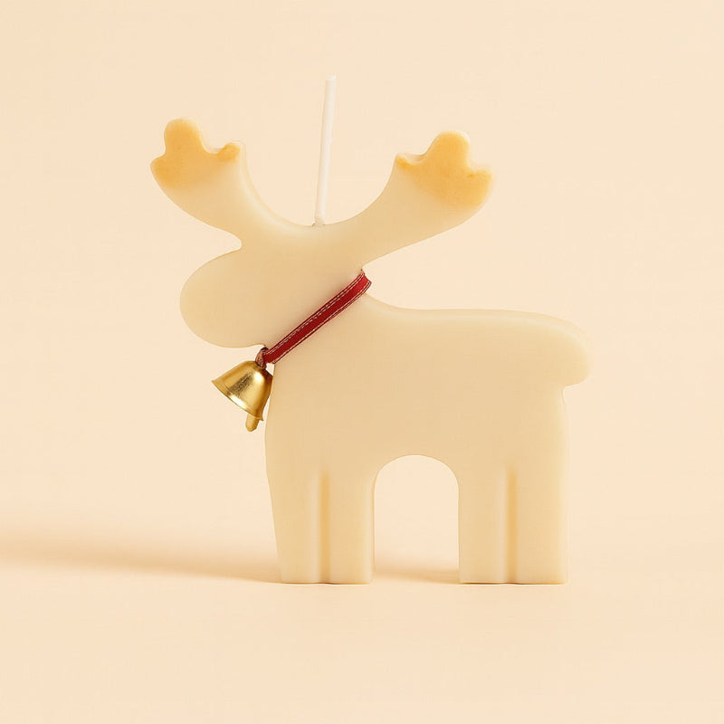 Bougie Noel Féérie du Renne Enchanté, de couleur blanc cassé et avec une clochette autour du cou. Sur fond beige.
