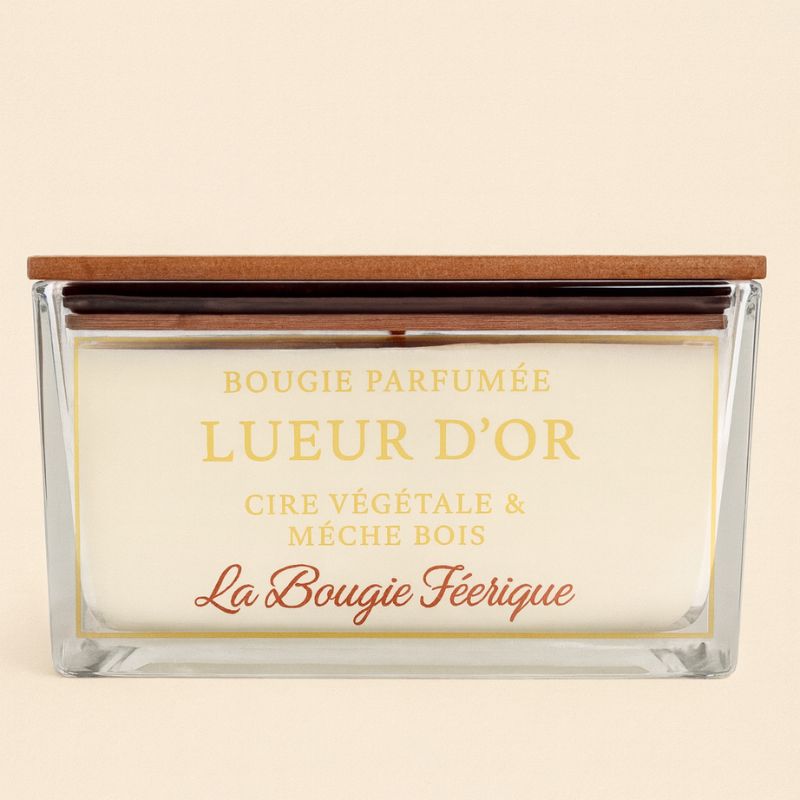 Bougie Parfumé Lueur D'Or, contenant en verre et couvercle en bois, sur fond beige clair.
