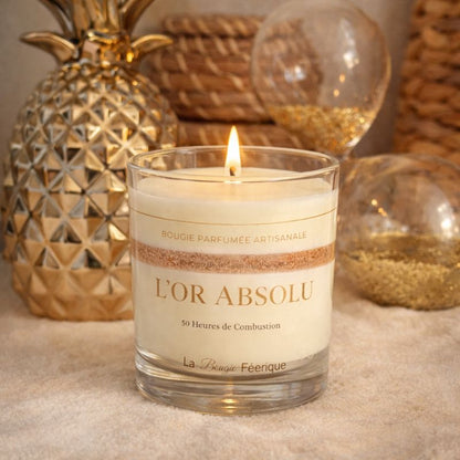 Bougie Parfumée Artisanale L’Or Absolu allumée dans une ambiance chaleureuse et élégante, décor doré et matières naturelles, lumière douce créant une atmosphère cosy et raffinée.