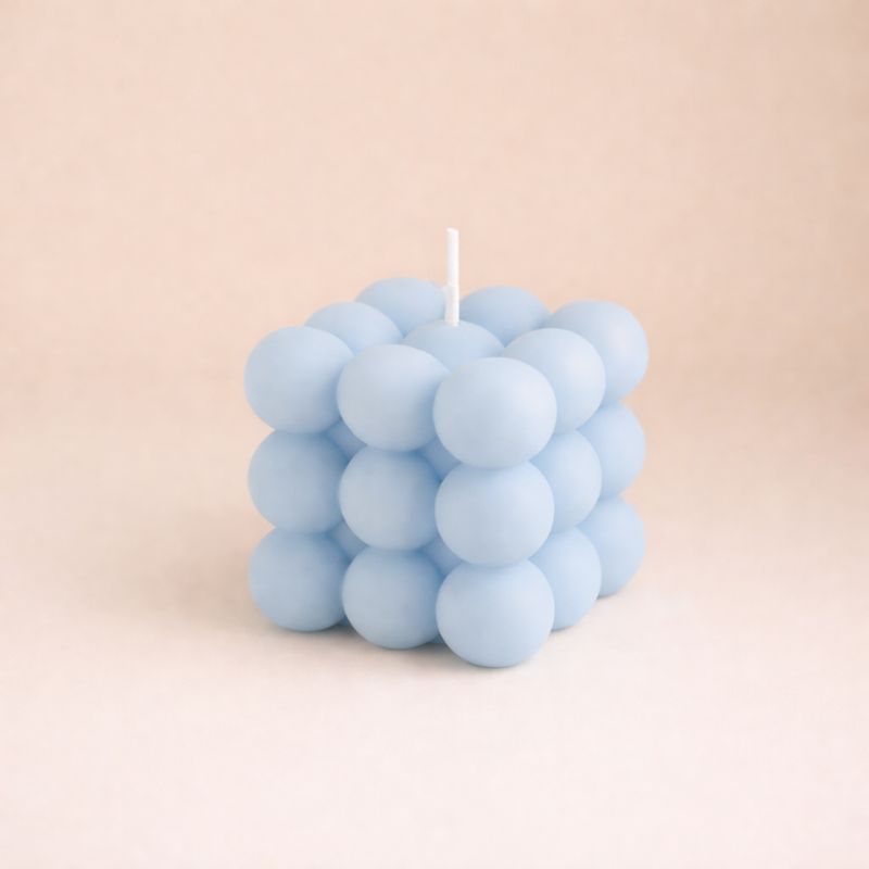 Bougie Parfumée Cube Design, de couleur bleu et de forme bubble carré. Sur fond beige clair.