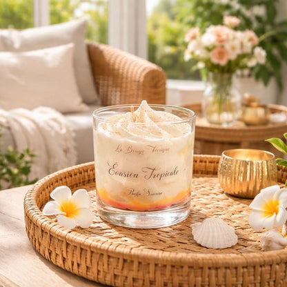 Bougie Parfumée Évasion Tropicale dans un verre décoratif posée sur plateau en rotin avec fleurs et coquillages pour une ambiance exotique et relaxante.