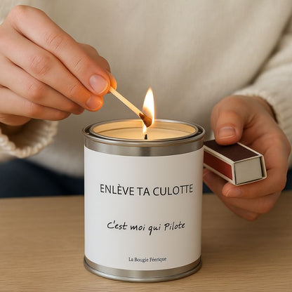 Bougie Personnalisée "Enlève ta Culotte C'est Moi qui Pilote", une personne allume la bougie avec une allumette.
